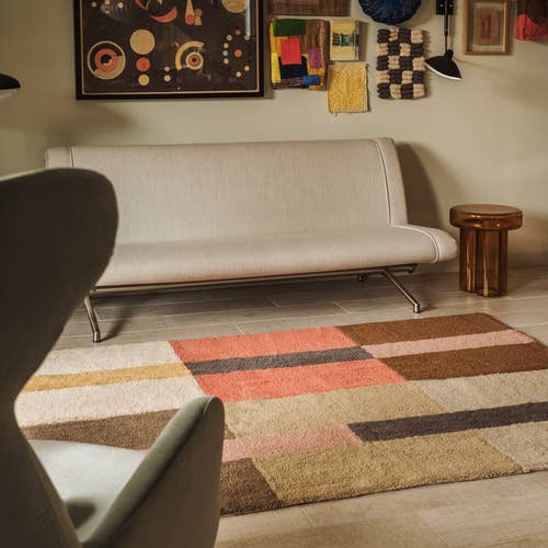 Beige sofa in a room with a colorful geometric rug on the floor.
