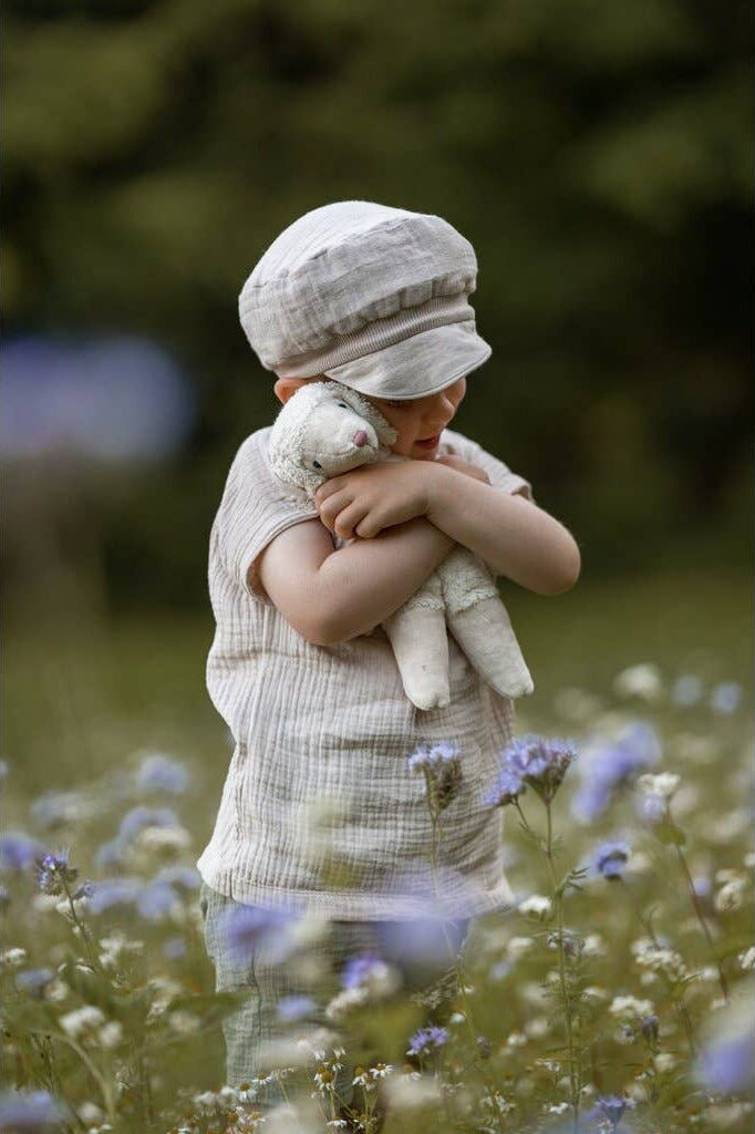 Child holding a teddy bear in a field of flowers