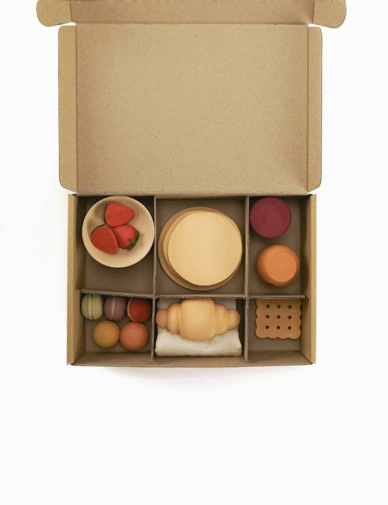 Set of wooden toys in a cardboard box on a white background