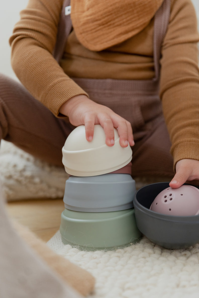 Child playing with colorful stacking toys on a soft surface
