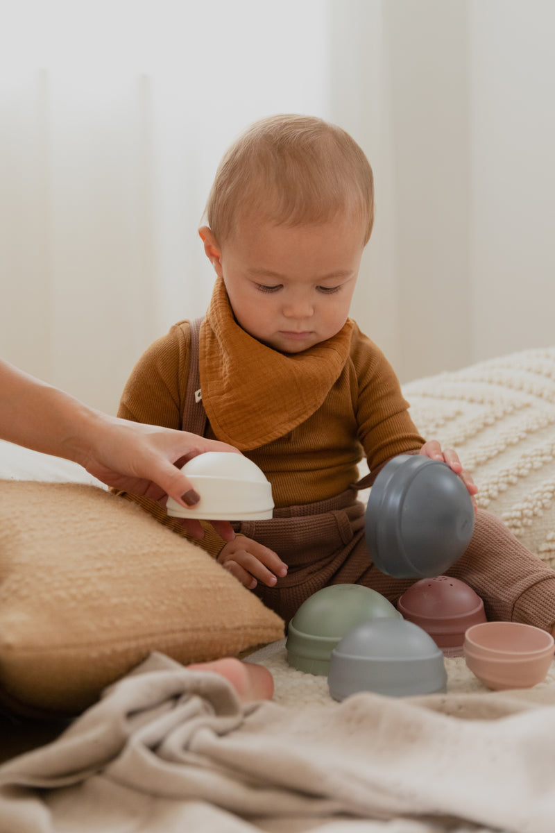 Child playing with colorful bowls on a soft surface