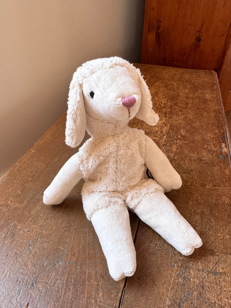 Plush bunny toy on a wooden surface with a neutral background