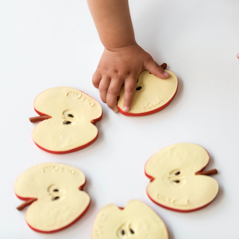 Child's hands interacting with apple slices on a white surface