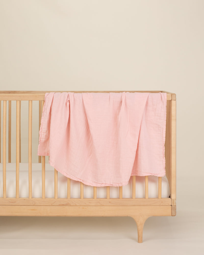 light pink organic cotton gauze swaddle on crib 